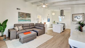 En moderne stue med en hjørnesofa, et køkkenområde og et spiseområde.