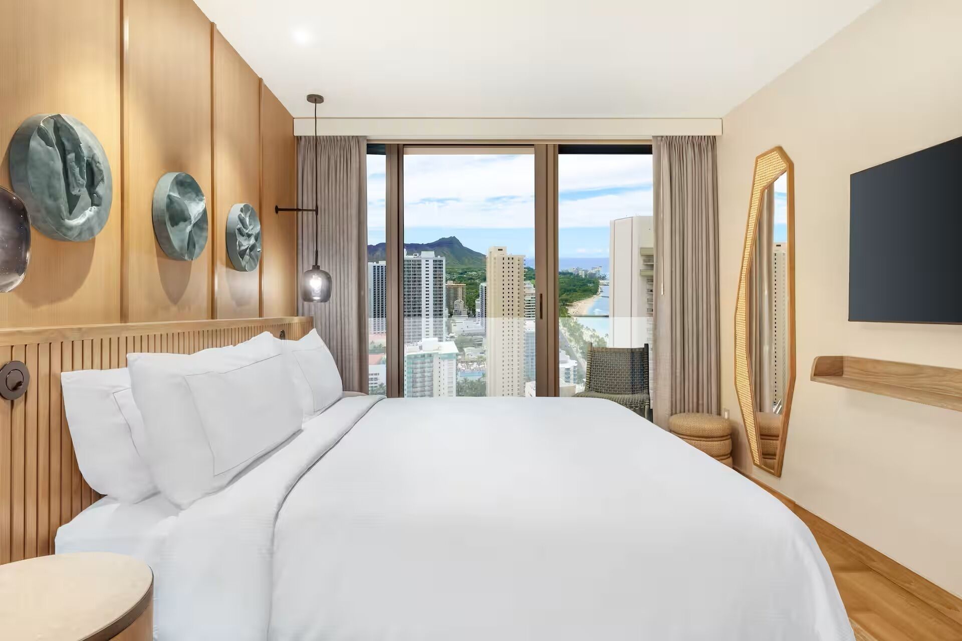 Une chambre d’hôtel avec un grand lit, une vue sur la ville et un miroir au mur.