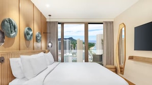 A hotel room with a large bed, a view of the city, and a mirror on the wall. - Waikiki | Relaxing Island Stay | Pool + Spa (Honolulu)