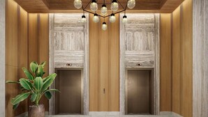An elevator with wooden paneling, a potted plant, and a modern light fixture. - Waikiki | Relaxing Island Stay | Pool + Spa (Honolulu)