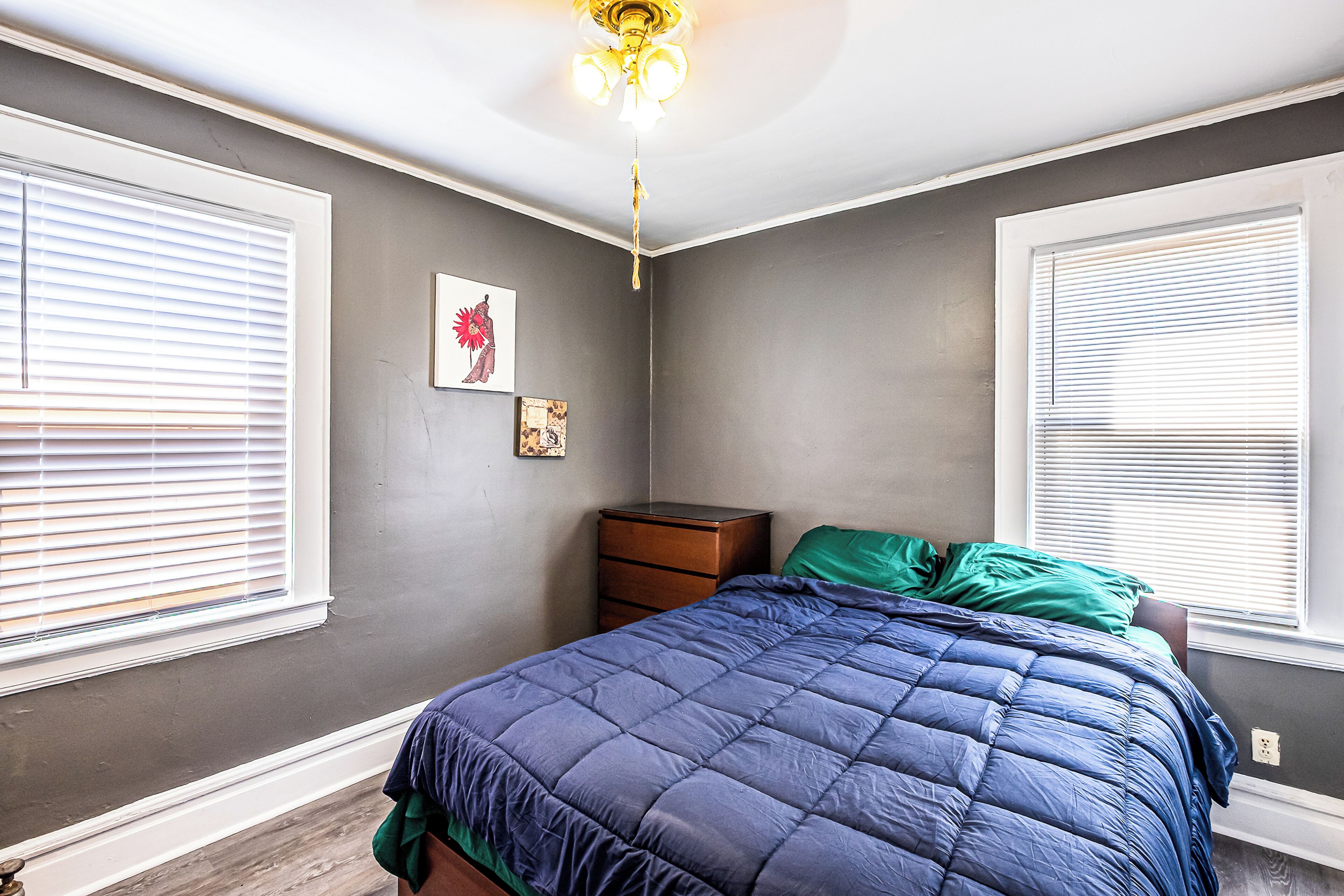 Un dormitorio con cama, cómoda y ventilador de techo.