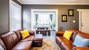 A living room with two brown leather sofas, a coffee table, and a door. - Orange Queen LLC (East Orange)