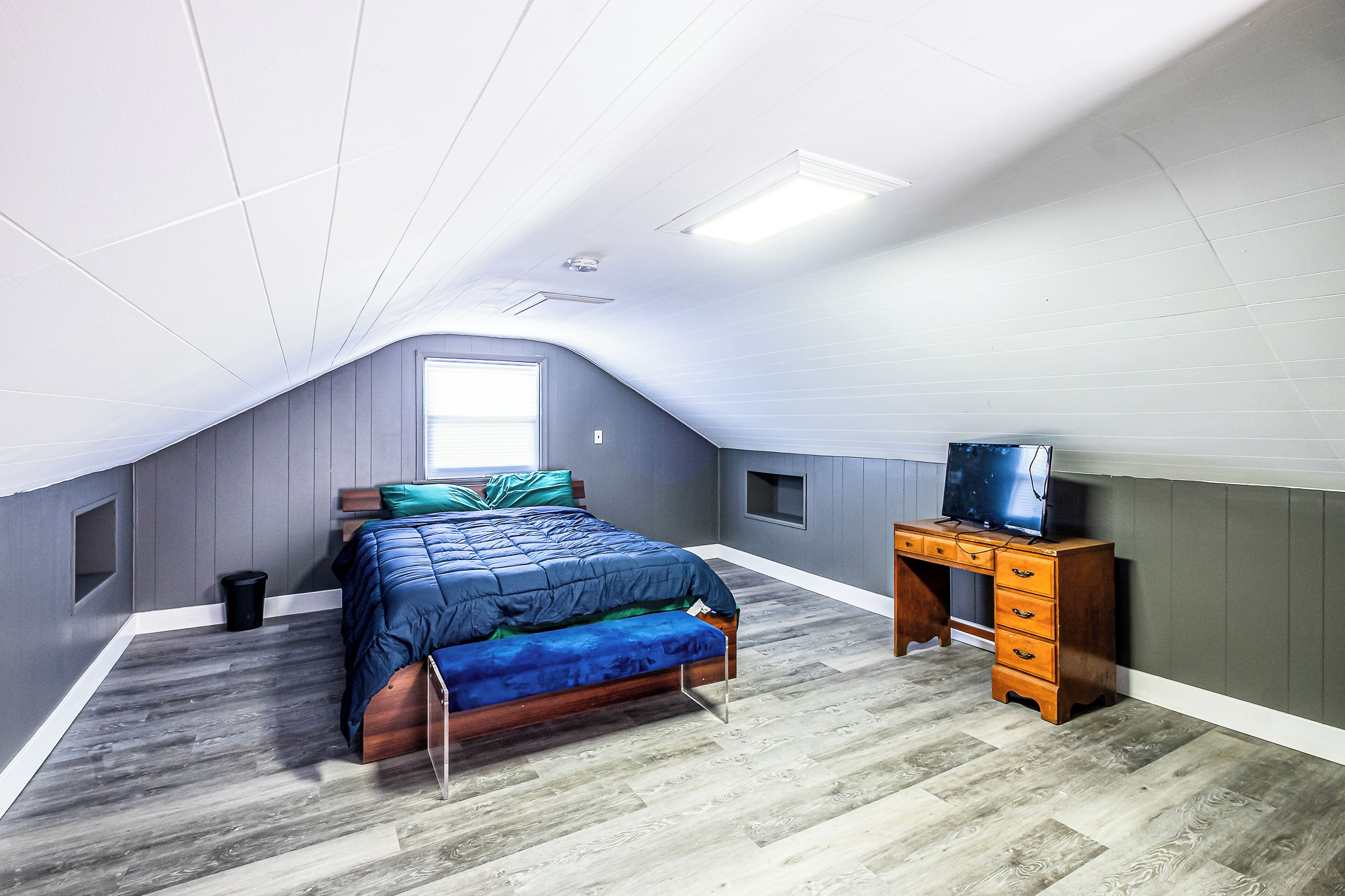 Une chambre à coucher avec un lit, un bureau, une télévision et une fenêtre.