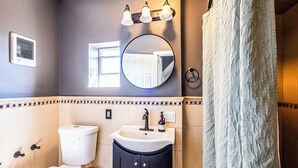 A bathroom with a toilet, sink, mirror, and shower curtain. - Orange Queen LLC (East Orange)