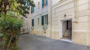 A narrow cobblestone street with a building featuring a staircase leading to an entrance. - Casa Crilù by BarbarHouse (Roma)