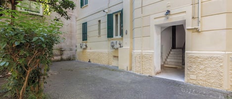 A narrow cobblestone street with a building featuring a staircase leading to an entrance.
