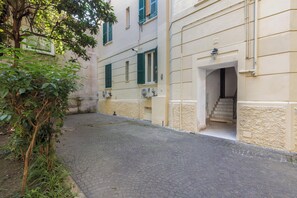Un carrer empedrat i estret amb un edifici que té una escala que condueix a una entrada.