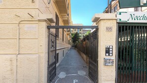 A narrow alleyway with a gated entrance, a sign indicating a condominium, and a building with a green gate labeled 'Nocchio'. - Casa Crilù by BarbarHouse (Roma)