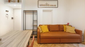 A living room with a brown sofa, a dining table, and a metal shelving unit. - Casa Crilù by BarbarHouse (Roma)