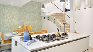 Una cucina moderna con isola centrale, un'area pranzo con sedie, una scala e vista sul piano superiore.