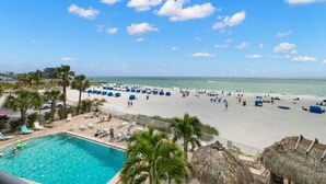 A beach resort with a swimming pool, lounge chairs, and a view of the ocean. - Beachfront Getaway with Resort-Style Pool (Madeira Beach)