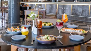Una mesa de comedor con diversos platos, bebidas y un jarrón de flores.