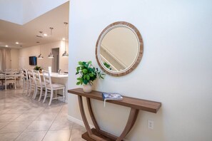 A modern kitchen with a dining area, a round mirror, a potted plant, and a wooden console table. - 6BR Disney Home w/ Pool at Windsor Cay (Clermont)