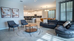A modern living room with a sofa, chairs, a coffee table, and artwork on the wall. - 6BR Villa w Pool & Game Room near Disney (Davenport)