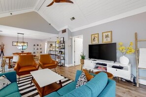 A living room with a sofa, chairs, a coffee table, a TV, and a bookshelf. - Relaxing Beach Condo w/Pool & Porch Access (Hilton Head Island)