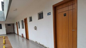 Un pasillo con puertas, un extintor y un cartel que indica la dirección de la salida.