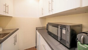 Una cocina con alacenas blancas, microondas y cafetera.