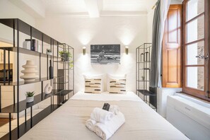 A hotel room with a large bed, a black metal bookshelf, a white vase, and a black and white photograph on the wall. - Cozy Studio A/C 2P - Saint-tropez (Saint-Tropez)