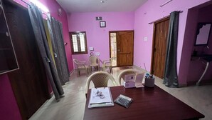 Una habitación con una mesa de madera, sillas, un escritorio, una ventana y una puerta.