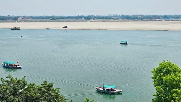 Ein Fluss mit Booten und ein sandiger Strand im Hintergrund.