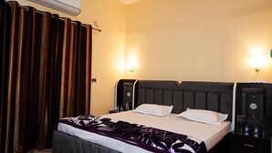 Ein Hotelzimmer mit einem Bett, zwei Nachttischen, einer Klimaanlage, einer Wandleuchte und einem Vorhang.