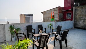 Eine Dachterrasse mit Tisch und Stühlen, Topfpflanzen und Blick auf das Meer.