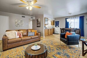 A living room with a brown leather sofa, a round coffee table, and a ceiling fan.