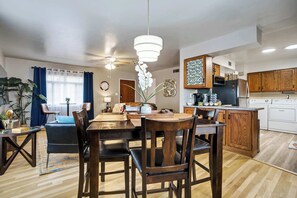 A modern kitchen with wooden cabinets, a dining area with a wooden table and chairs, and a ceiling fan.