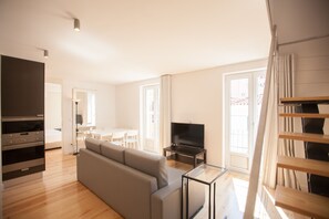 Ein modernes Wohnzimmer mit einer Couch, einem Fernseher und einem Essbereich.