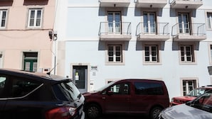 En byggnad med flera våningar, balkonger, en grön dörr och en skylt som visar texten ”Eighty Plus”.