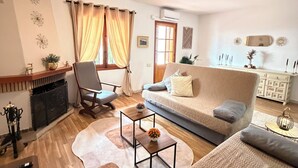 Una sala de estar con sofá, una mesa de centro, chimenea, una silla y un comedor con un aparador.
