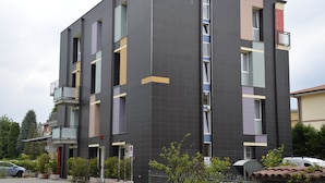 A multi-story building with balconies, a parking area, and potted plants. - La Formica (Savignano sul Panaro)