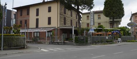 A hotel with a stone facade, a covered entrance, and a signboard.