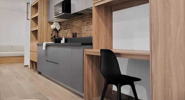 A modern kitchen with grey cabinets, a black chair, and a wooden accent wall. - Colonia Americana Safe Neighborhood for World Cup (Guadalajara)