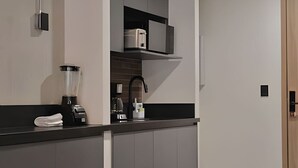 Een moderne keuken met een ingebouwde koffiemachine, een blender en een waterkoker op het aanrecht.