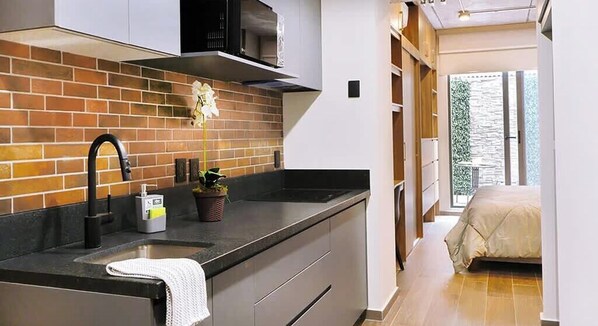 Eine moderne Küche mit Backsteinwand, einem schwarzen Wasserhahn und einem Blumentopf.