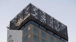A tall hotel building with a modern facade, large windows, and a prominent sign at the top. - Cozy 1-bedroom apartment in beautiful Riyadh with AC and gym access (Riyadh)