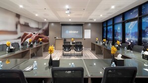 A modern conference room with glass tables, black chairs, and a large screen displaying hotel branding. - Cozy 1-bedroom apartment in beautiful Riyadh with AC and gym access (Riyadh)