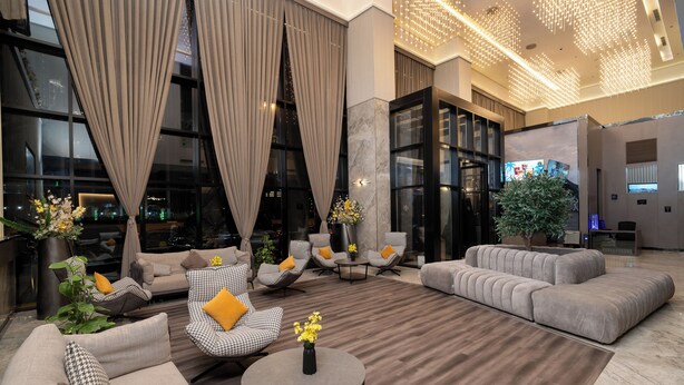 A spacious lobby with modern seating, large windows, and a decorative ceiling light fixture. - Cozy 1-bedroom apartment in beautiful Riyadh with AC and gym access (Riyadh)