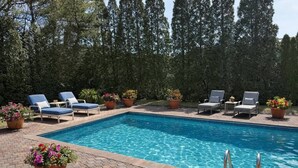 Ein rechteckiger Swimmingpool mit klarem, blauem Wasser, umgeben von Liegestühlen und Blumentöpfen.