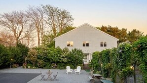 Ein Haus mit Terrasse, Sitzgelegenheiten im Freien und Pflanzgefäßen.