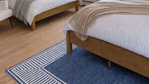 Ein Schlafzimmer mit zwei Betten, einem Fenster und einem blauen Teppich.