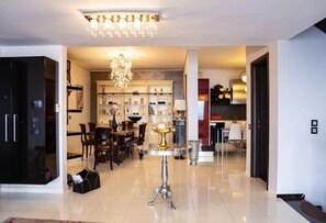 Un salon moderne avec un lustre, un coin repas et une cuisine en arrière-plan.