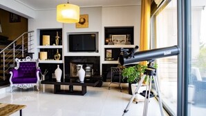 A modern living room with a fireplace, a mounted telescope, and a purple armchair. - Elegant Nian Villa Sea - Luxury Stay in Drosia, Chalkida (Chalkida)