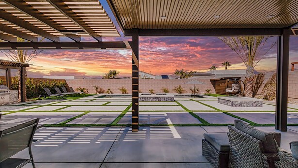Una veranda coperta con vista sul tramonto, un'area salotto con divano e poltrone, e una struttura a pergola.