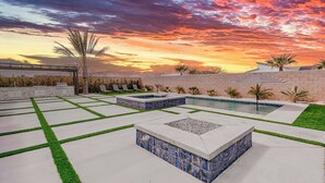 Area piscina con cielo al tramonto, motivi a mosaico geometrici e un muro in mattoni.