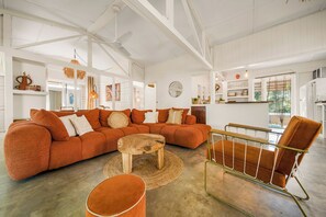 Ein geräumiges Wohnzimmer mit einem großen Ecksofa, einem Holztisch und einem Metallstuhl.