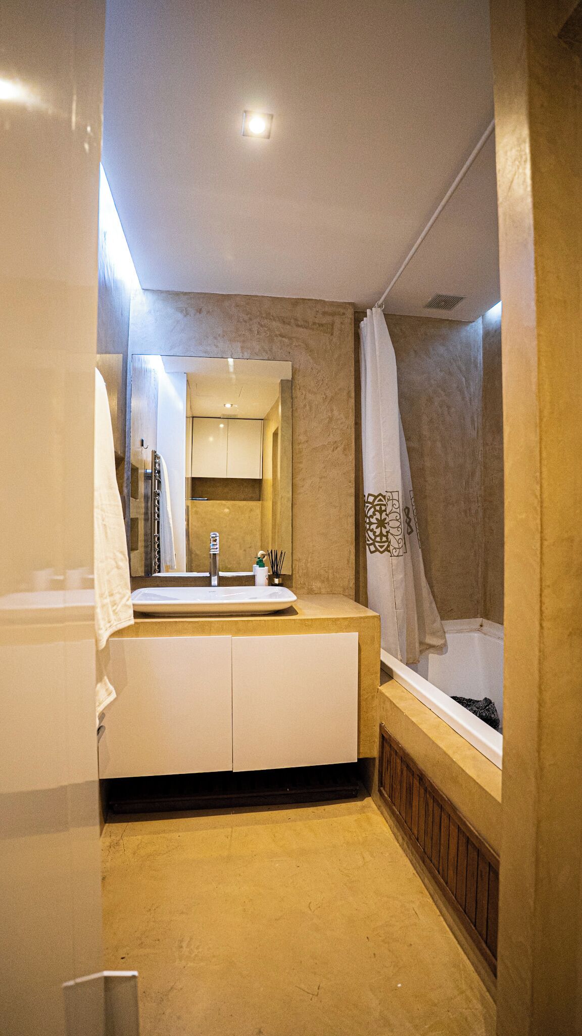 Een badkamer met een wastafel, spiegel en bad.