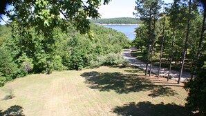 A grassy area with trees and a view of a body of water. - 4-bedroom house overlooking Lake Norfork with AC comfort (Mountain Home)