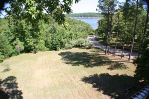 A grassy area with trees and a view of a body of water. - 4-bedroom house overlooking Lake Norfork with AC comfort (Mountain Home)